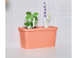 Speelgoed plantenbak met houten plantjes tegen een witte tegelwand.