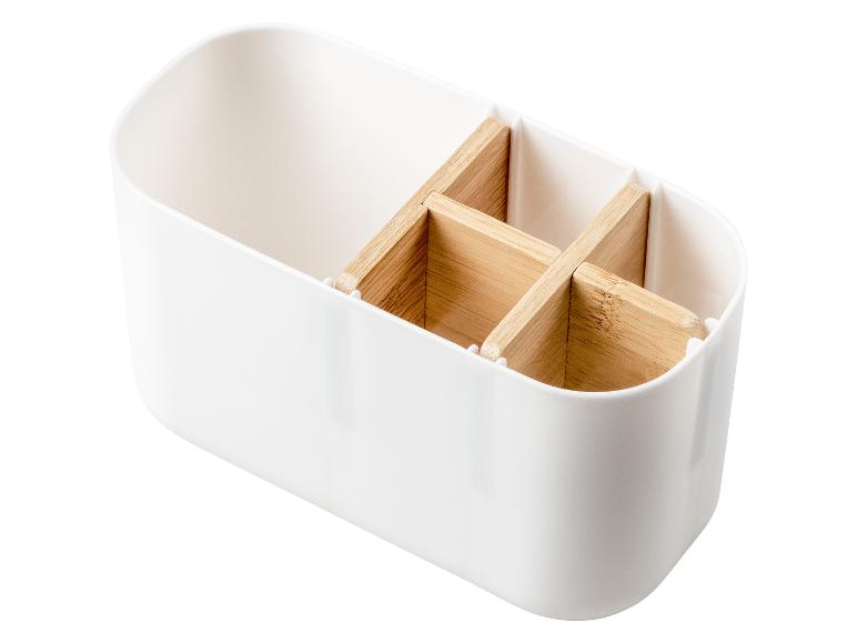 Een wit opbergbakje met houten inzetstukken voor bestek.