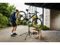 Man repareert elektrische mountainbike op reparatiestandaard met gereedschap ernaast.