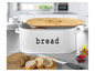 Een witte broodtrommel met een houten deksel en brood ernaast