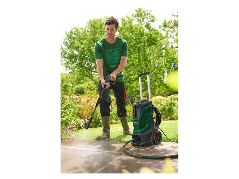 Man reinigt een terras met een hogedrukreiniger in een tuin.