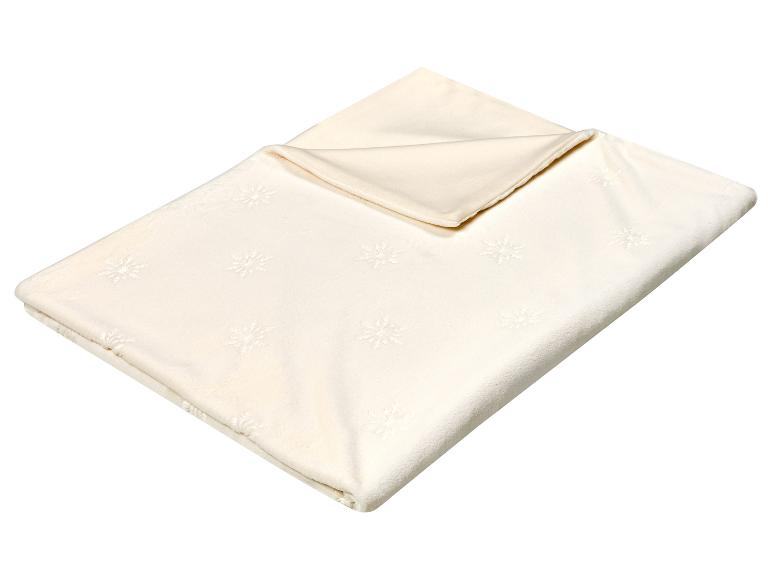 Crèmekleurige deken met sneeuwvlokkenpatroon, opgevouwen en klaar voor gebruik.