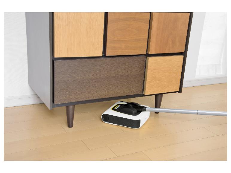 Elektrische veger reinigt onder een houten kast met deuren in verschillende tinten.
