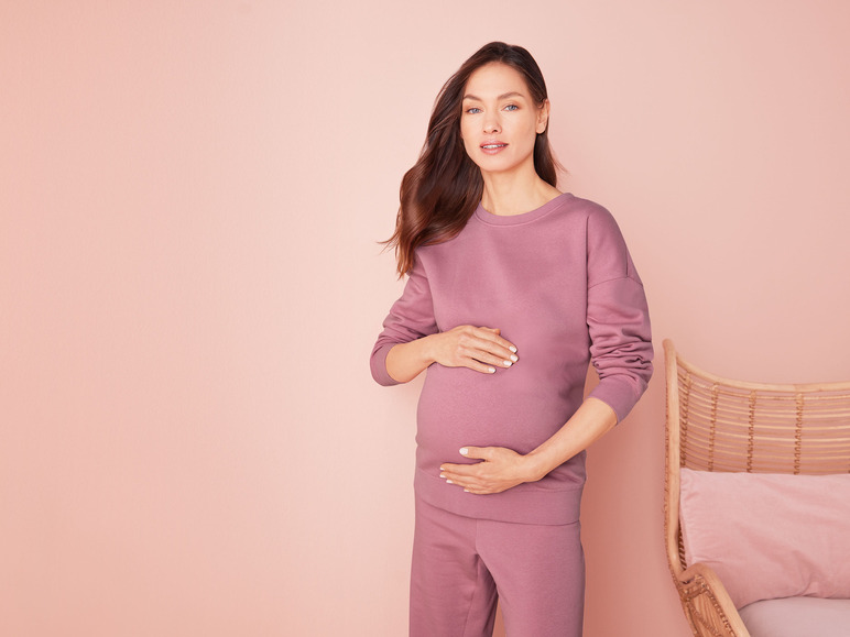 Een zwangere vrouw in een roze joggingpak.