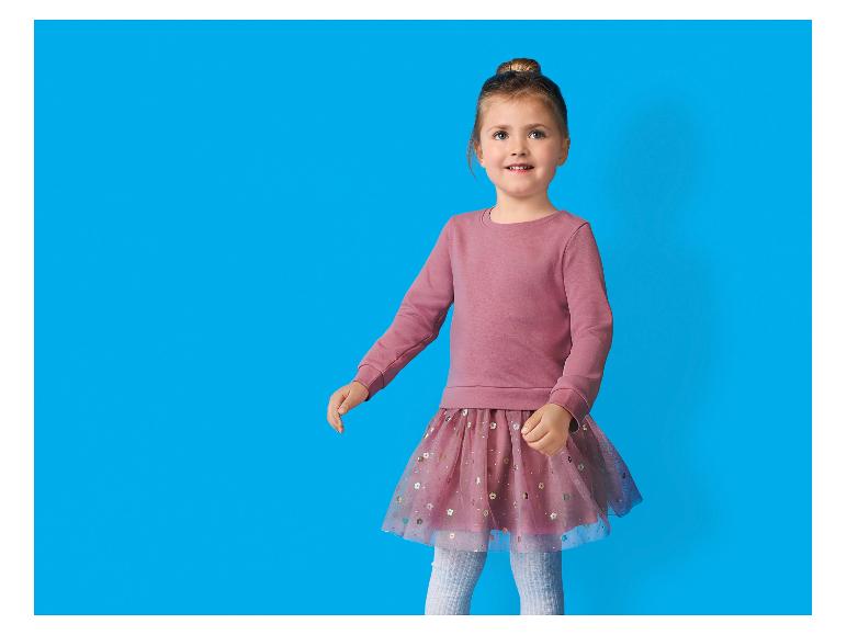 Meisje in roze sweatshirt en tule rok met pailletten.