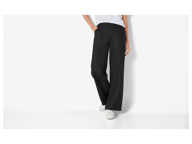 Zwarte wijde broek en witte sneakers.