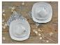 Twee witte serviessets met kopjes op een houten tafel met decoratieve planten.
