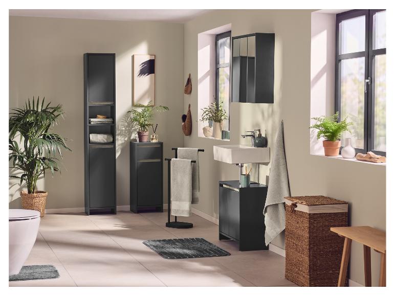 Badkamer met zwarte kasten, wastafel, toilet, planten en textiel.