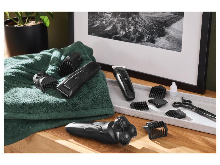 Elektrisch scheerapparaat, tondeuse en accessoires op een handdoek en dienblad.