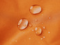 Waterdruppels op een oranje, waterafstotend textiel.