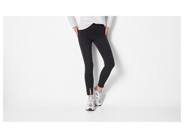 Vrouw in een strakke zwarte broek en wit-grijze sneakers.
