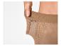 Vrouwenhand rekt de tailleband van een huidkleurige panty uit, wat de elasticiteit toont.