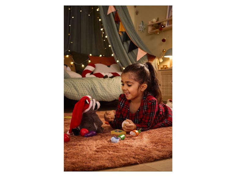 Een meisje speelt met een pluche wasbeer en houten speelgoed in een kinderkamer.