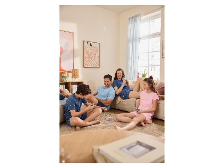 Familie in pyjama speelt kaarten in de woonkamer.