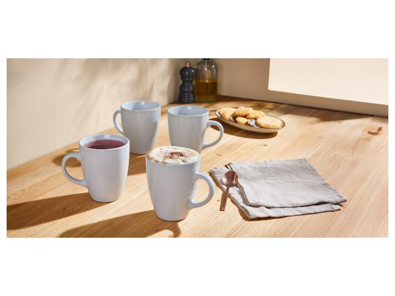 Drie koffiemokken en koekjes op een houten tafel.