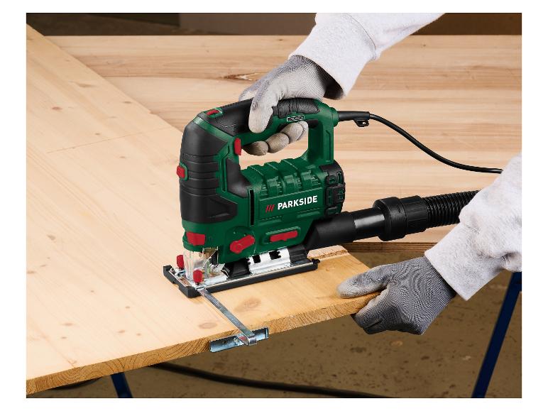 Een persoon zaagt een houten plank met een elektrische zaag, met beschermende handschoenen.