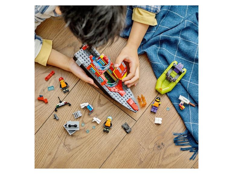 Kind speelt met speelgoedboten en figuren op een houten vloer.