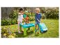 Twee kinderen spelen met een water- en zandtafel, een bellenblaasmachine en een rijdend speelgoed in een tuin.