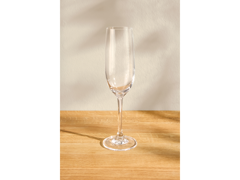 Leeg champagneglas op een houten oppervlak met een lichte achtergrond.