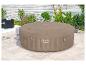 Opblaasbare hot tub op een terras met planten en een wit hek op de achtergrond.