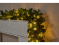 Kerstslinger met warmwitte LED-lampjes gedrapeerd over een witte schouw.