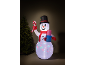 Opblaasbare sneeuwpop met hoge hoed, zuurstok en cadeau, naast een kerstboom.