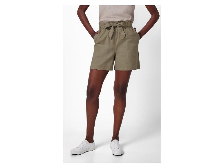 Model draagt een kaki short met hoge taille en strik en witte sneakers.