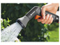 Een hand houdt een Gardena sproei-kop vast die water spuit.