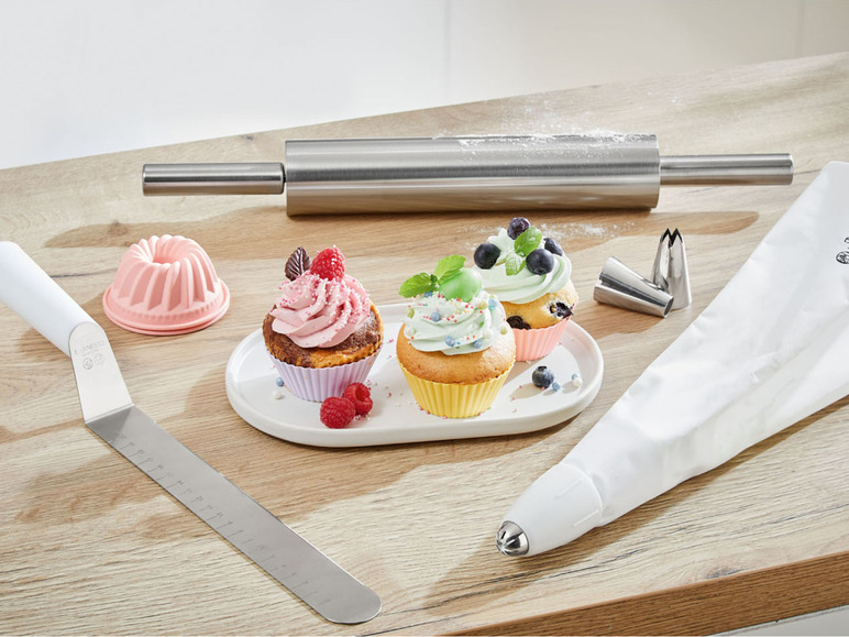 Een roldeeg, spuitmondjes en cupcakes met verschillende versieringen.