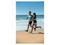 Twee mensen rennen in sportkleding op een strand.