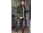Man in olijfgroene pufferjas, grijs T-shirt en donkere jeans met een riem.