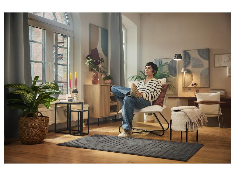 Een persoon die ontspant in een moderne en gezellige woonkamer op een fauteuil.