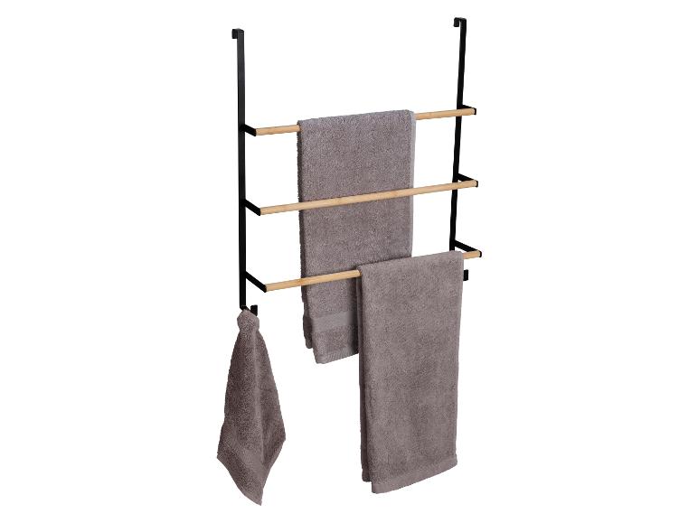 Drie handdoeken hangen aan een zwarte handdoekhouder met houten latten.