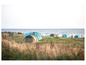 Tenten staan opgesteld op een grasveld met uitzicht op zee.