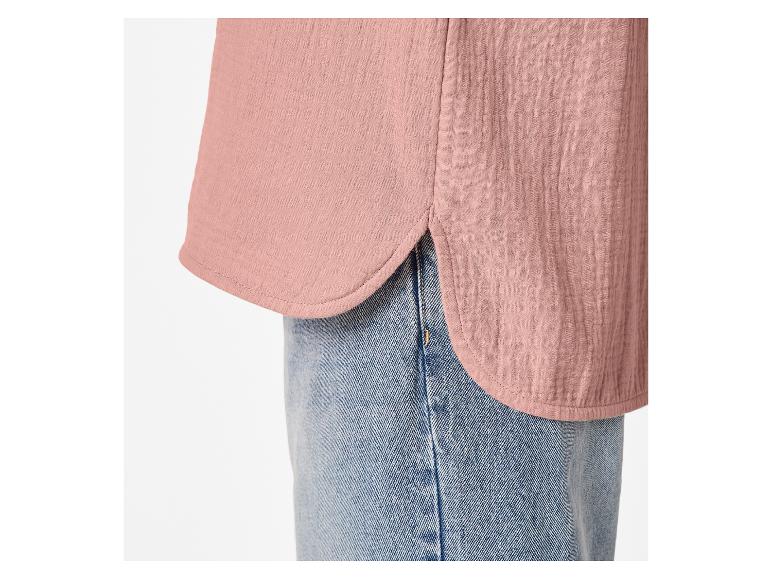Detail van een roze mousseline overhemd met een afgeronde zoom en blauwe jeans.