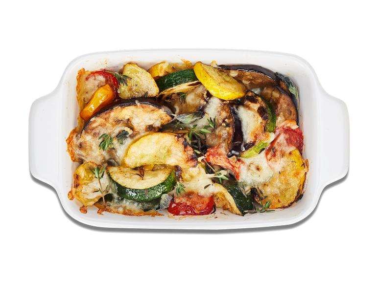Gegrilde aubergine, courgette en paprika met kaas in een ovenschaal.