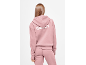 Vrouw in een roze hoodie en joggingbroek, met witte tekst op de rug.