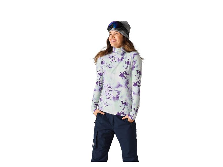 Vrouw in paars en mintkleurig ski-shirt, donkerblauwe skibroek, met skibril en muts.