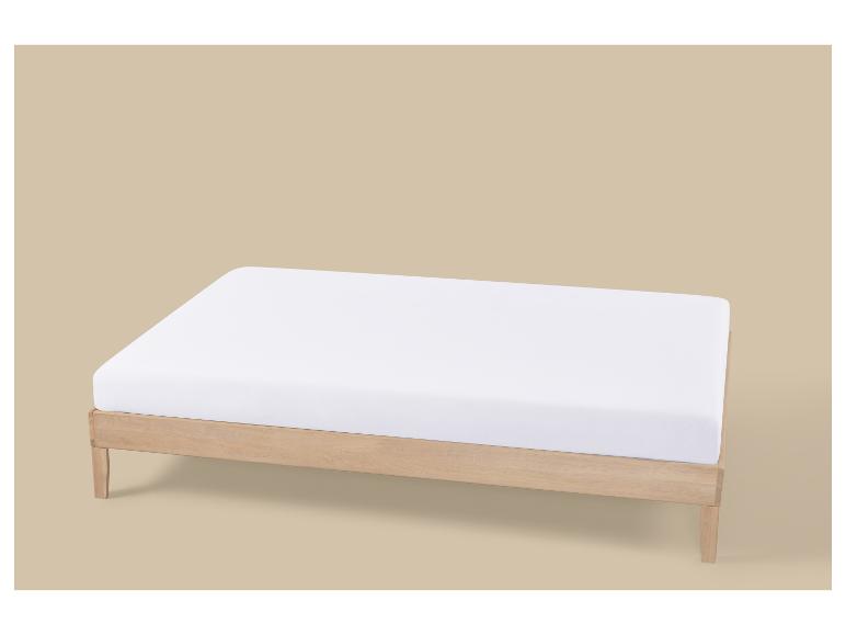 Licht houten bed met wit matras op beige achtergrond.