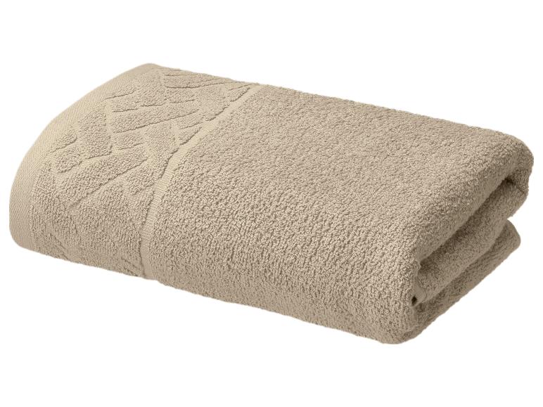 Gevouwen beige handdoek met een subtiel patroon langs de rand.