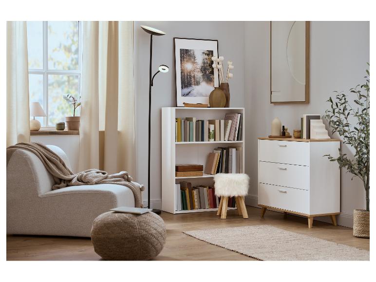 Gezellige woonkamer met fauteuil, boekenkast, ladekast en vloerlamp.