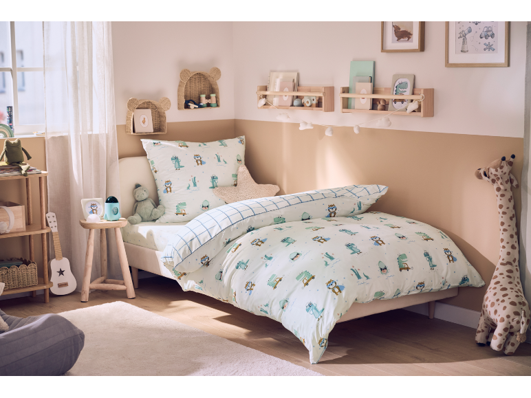 Gezellige kinderkamer met een bed met dinosaurusbeddengoed en speelse decoratie.