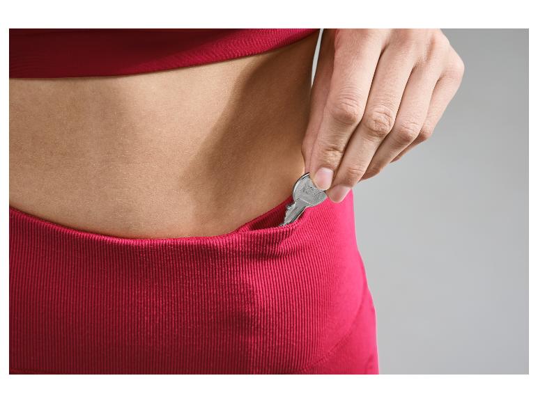 Een hand stopt een sleutel in een roze broekzak.