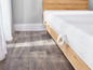 Een wit matras met houten lattenbodem en witte gordijnen.