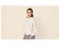 Meisje in beige hoodie en jeans, glimlachend.