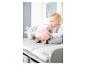 Baby zit op een commode met knuffels, een roze en een blauwe.