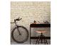 Een fiets en een donkerhouten bureau met een kruk tegen een lichte bakstenen muur.