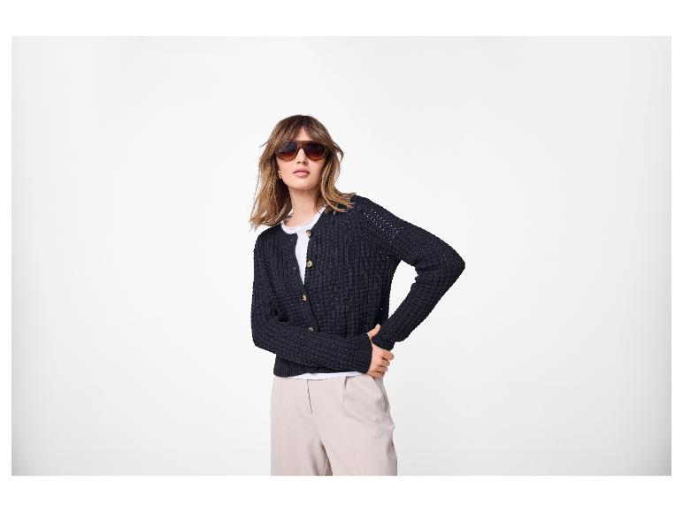 Vrouw in zwart vest, wit T-shirt en beige broek, met zonnebril