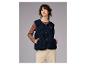 Vrouw in een marineblauwe fleecevest, bruine top en beige broek.