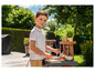Een jongen die met een speelgoed barbecue en kookgerei speelt.
